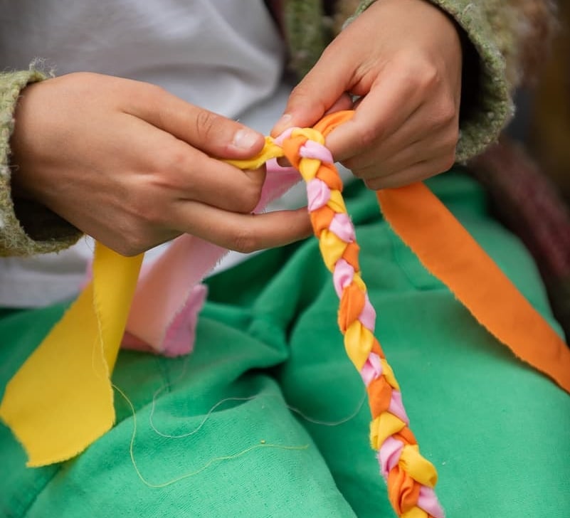Hands braiding with ribbon.