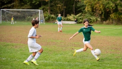 Girl kicking soccer ball with boy.