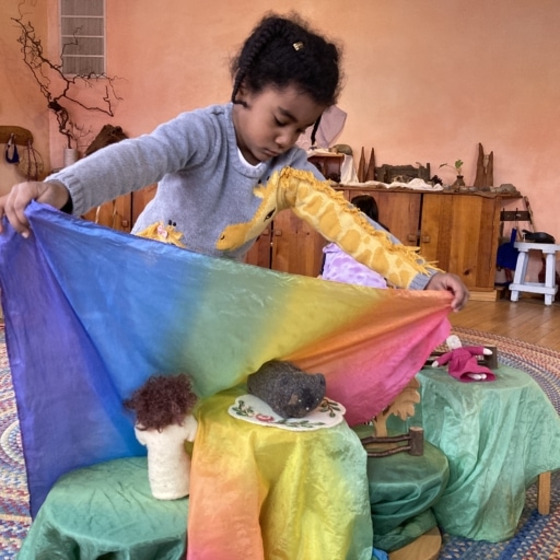 Girl covering toys with colorful blanket